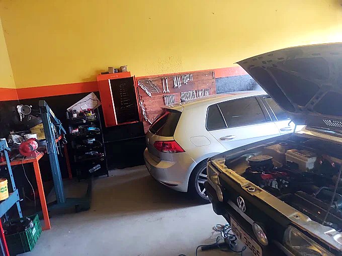 Interior da oficina Stop Car com Golf VW em manutenção, parede de ferramentas organizadas e elevador hidráulico